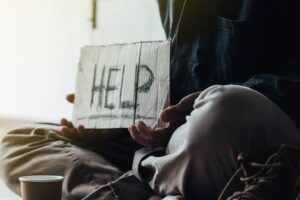 Poor tired depressed hungry homeless man holding cardboard card with "help" handwritten text. nostalgia and hope concept.